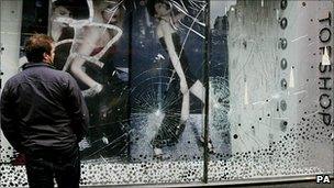 A man inspects damage to the windows of Topshop in Oxford Street