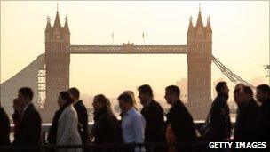 City workers cross London Bridge with Tower Bridge in the background