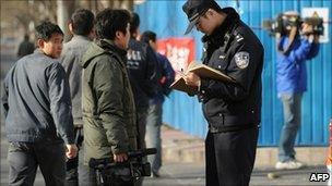 Policeman checks identity papers of journalist in front of Liu Xiaobo's apartment in Beijing - 10 December 2010