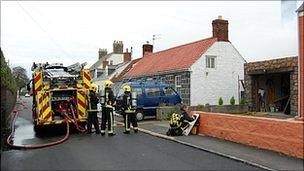 Guernsey fire engine and firefighters damping down shed fire