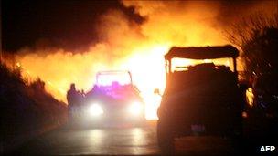 Mexican federal police officers stand by a burning blockade set up by drug cartel gunmen in the western state of Michoacan