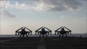 Three planes sitting by the runway on the USS George Washington