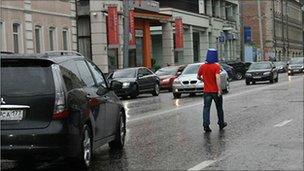 Voina president Leonid Nikolayev walks down the street with a blue bucket on his head