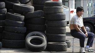 A dealer sits next to tyres on display at a tyre shop in Beijing