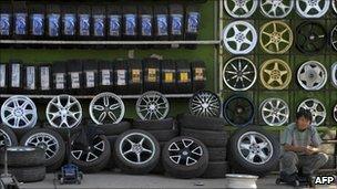 A man sits next to tyres on display at a tyre shop in Beijing
