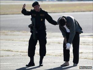 Guatemalan police officer escorts a suspected member of the Zetas at Guatemala City airport on 9 December 2010