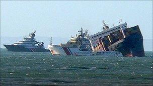 A coastguard ship in front of the stricken MSC Napoli