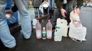 People filling up bottles and containers with water