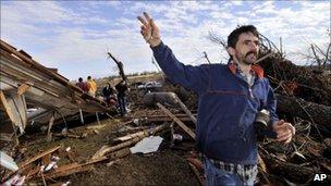 A man standing near debris from a tornado in Arkansas