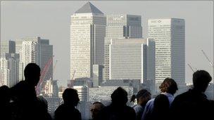 Workers silhouetted in front of London's Canary Wharf skyline