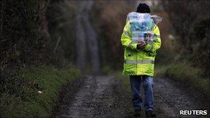 Man walks along country lane carrying bottles of water