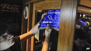 A man removes a sign saying that smoking is allowed in a bar in Pamploma, Spain, 2 January 2011