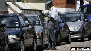 A traffic warden inspecting parked cars