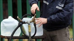 An employee of Northern Ireland Water fills plastic containers for members of the public outside the company's headquarters in North Belfast on 31 December 2010