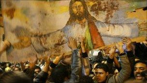 Egyptian Christians hold a blood-stained portrait of Jesus Christ during a protest in Alexandria, 2 January