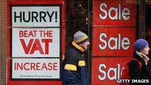 Shoppers pass a sign urging them to hurry and beat the VAT increase