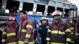 Firefighters beside the scorched bus and the covered body of one of the victims in Guatemala City (3 January 2011)