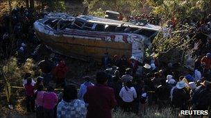 People stand around a bus after it plunged into a ravine near San Marcos in western Guatemala