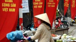 A street vendor walks past banners promoting the party congress in Hanoi on 6 Jan 2011