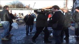 A man holding a metal pole rushes towards the film crew