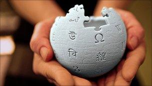 Hands holding the wikipedia symbol