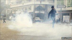 Protesters walk through tear gas during clashes with riot police in downtown of the capital Tunis January 14, 2011.