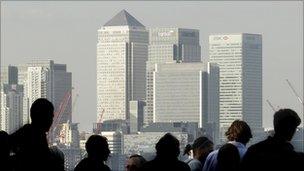 Workers silhouetted in front of the Canary Wharf skyline, London