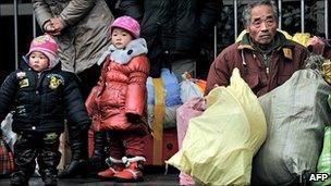 Two children look on next to a man waiting with his luggage at the railway station in Shanghai, China, 19 January 2011