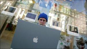 Man on a laptop outside a shop