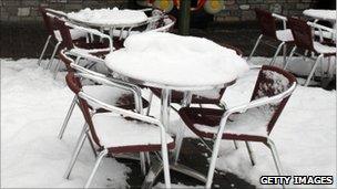 Snow on tables outside a closed cafe