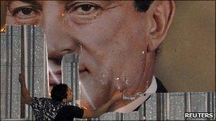 Poster of President Mubarak being torn down by protester.