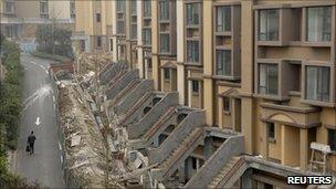 A man walks past buildings under construction at a residential complex in Chongqing municipality