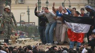 Protestors stand on army tanks in Tahrir Square