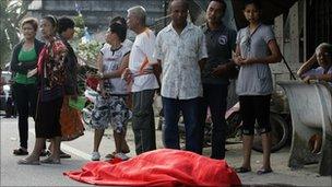 People stand next to the body of one of the victims of the shooting in Pattani on 3 Feb 2011