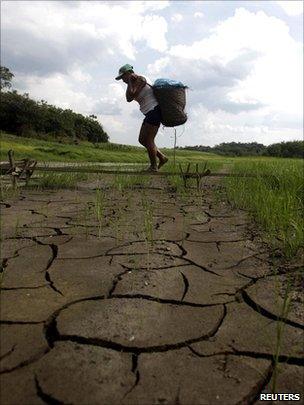 Man carring basket across dry ground