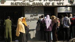 Egyptians wait at an automatic cash dispenser in Cairo