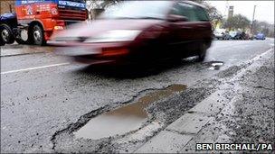 Car drives past pothole