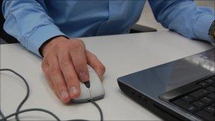 Man holding a mouse attached to a laptop