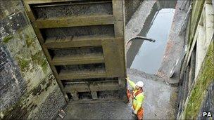 A workman steadies the three tonne solid oak lock gate into place