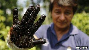 Environmentalist Donald Moncayo shows his glove after conducting a test made on an affected field in Lago Agrio, 25/01