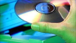 Man's hand placing CD in computer tray (Pic: Eyewire)