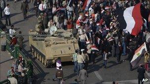 Demonstrators walk by an army vehicle in Tahrir Square on 18 February.