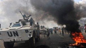 UN peacekeepers drive past supporters of Alassane Ouattara as they demonstrate in the Abobo neighbourhood in Abidjan on 19 February 2011
