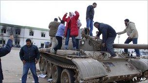 Residents stand on a tank inside a security forces compound in Libya