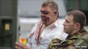 A man is escorted by a rescue worker after being pulled from a destroyed building in Christchurch, 23 February 2011