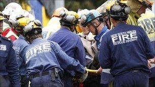 Rescue workers tend to a woman as she is lifted clear of the wreckage of the collapsed Pyne Gould Corporation (PGC) building, 23 February 2011