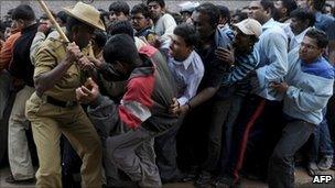 An Indian policeman uses a bamboo stick to beat back cricket fans outside Bangalore's Chinnaswamy stadium on 24 February 2011
