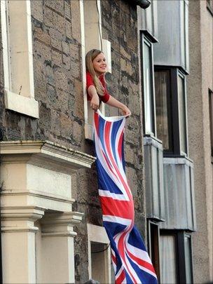 girl waves flag out window