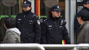 Policemen watch passers-by along the shopping street of Wangfujing in Beijing, 27 February 2011