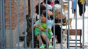 The daughter of two migrant workers waits to register outside an unlicensed school in Beijing on 10 August 2010